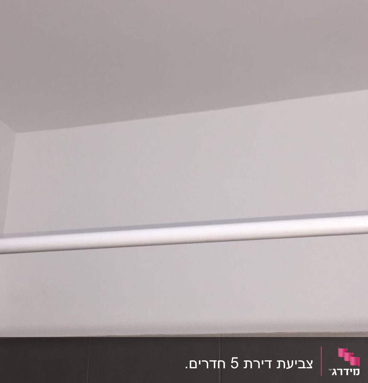 קיר צבוע בלבן עם מוט תלייה לבן
